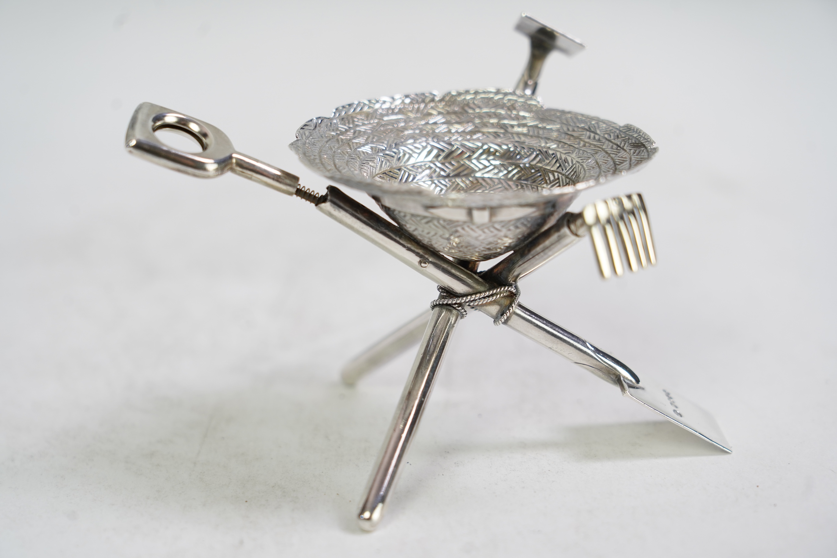 A rare Victorian novelty silver smoker's compendium set, modelled as an upturned straw hat with gardening tools tripod support, by Jane Brownett